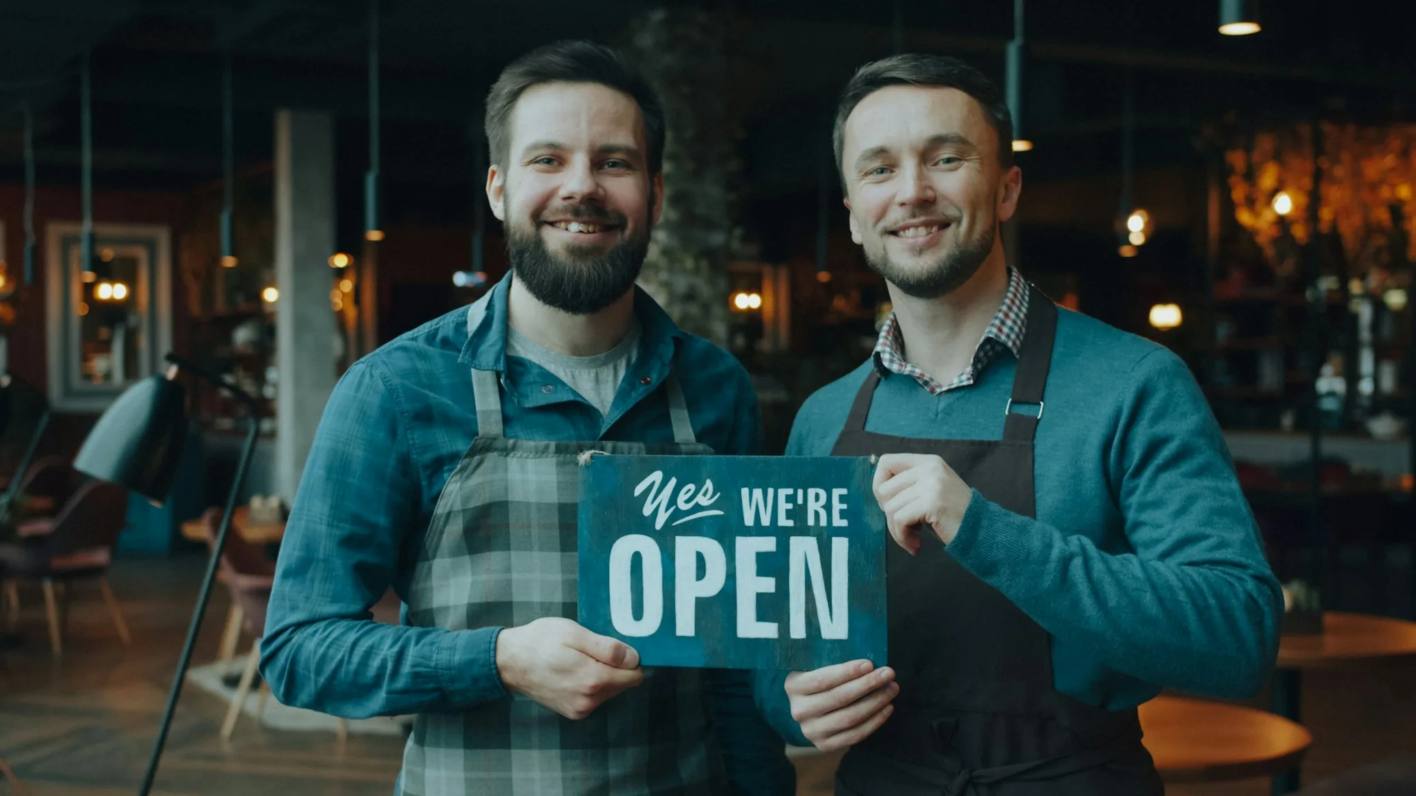 Restoranının önünde açık tabelası tutan iki işletme sahibi